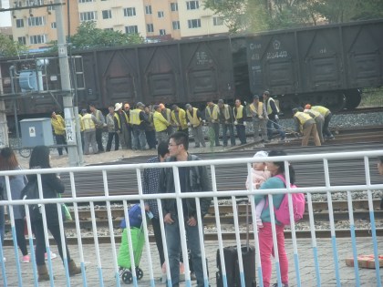 A gaggle of workers trying to move a giant beam by hand.